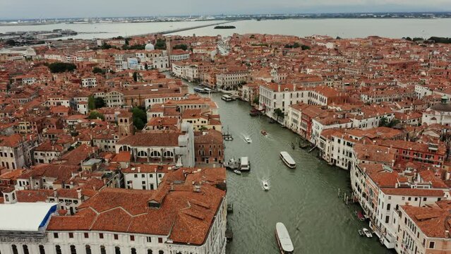 View from above of the Grand Canal with ships sailing along it and old traditional houses with orange roofs in the historic center of Venice. Italy. Drone video