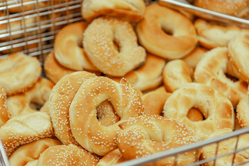 Homemade traditional bagels with sesame ready for use, in a tray with a tong, in bakery shop