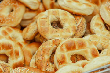 Homemade traditional bagels with sesame ready for use, in a tray with a tong, in bakery shop, selective focus
