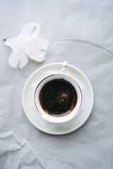 cup of coffee and white flower on gray background. top view 