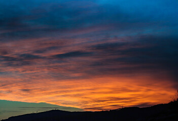 cloudy sunset with orange clouds and mountain silhouettes
