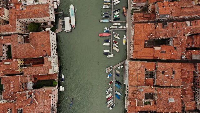Top view of the Grand Canal with empty gondolas tied to the pier. Traditional houses on both sides of the canal, drone footage on a sunny day. Venice, Italy