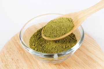 Bowl of green tea matcha powder in a wooden spoon on a white background