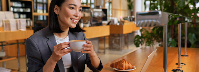 Happy smiling young Asian business woman entrepreneur or student having coffee break relaxing after...