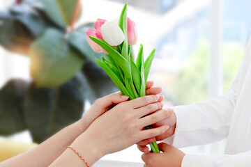 Beautiful tulip bouquet on hand, daughter giving flowers for her mother and mom taking them, warm love in family, Happy mother day, kid have special time with mom.