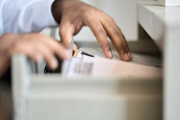 Male hands of teacher, accountant or cleck searching corporate documents in archive drawer. Files reference directory administrator looking for papers, doing paperwork, organizing storage. Close up