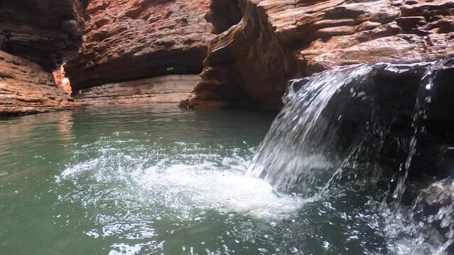 Small waterfall in Kermits Pool swimming hole located in a canyon at the end of the Spider Walk at Hancock Gorge in Karijini National Park, Pilbara region Western Australia.