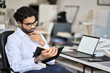 Busy indian business man planning agenda looking in notebook organizer thinking on calendar daily...