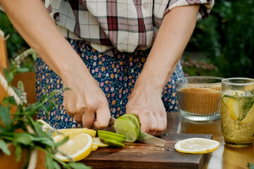 Woman hands cuts lemons and limes for summer lemonade drink.