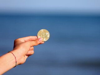 hand holding a golden coins with the letter B symbolizing the bitcoin cryptocurrency