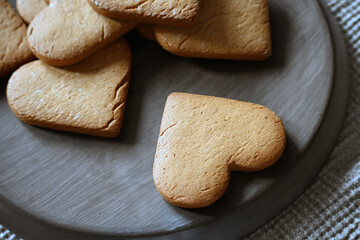 Shortbread cookies in the shape of hearts are on a ceramic tray. Homemade cakes. 