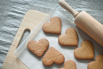 Shortbread cookies in the form of hearts are baked for a home tea party. Baking, wooden rolling pin. 