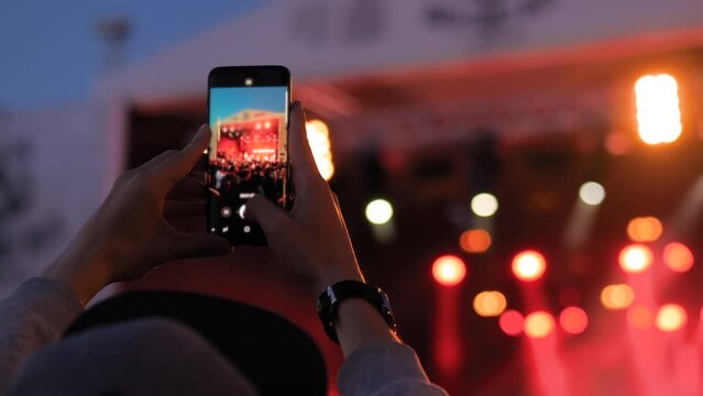 Man hands taking photo or recording video of live music concert with smartphone in front of stage of nightclub - close up. Photography, entertainment, technology concept