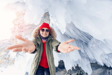 Woman traveler in red hat background of frozen grotto and pure ice winter Lake Baikal