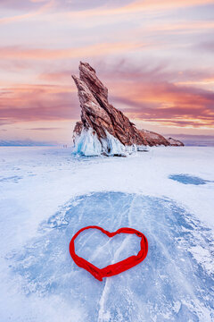 Beautiful winter landscape island Ogoy frozen lake Baikal blue ice with red hearth love sunset light