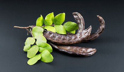 Carob. Healthy organic sweet carob pods with seeds and leaves close up. Healthy eating, food...