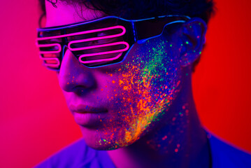 Fashion model with fluo painting on the face - Cool handsome young man with florescent creative make-up 