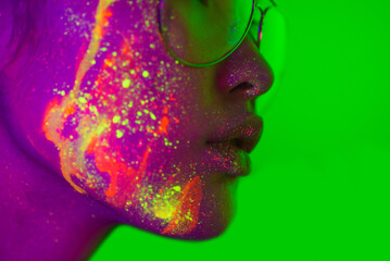 Fashion model with fluo painting on the face - Creative fashion portrait of young beautiful asian woman with fluorescent make-up, futuristic and metaverse concept