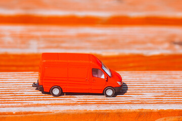 Red toy delivery van on red wooden background