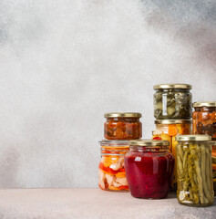Preserving vegetables for the winter, canned vegetables in jars on a light background, pickled or fermented vegetables, copy space
