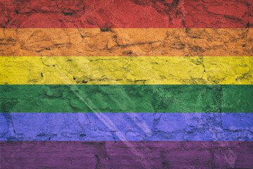 LGBT pride flag on stone wall, grunge background. Rainbow flag depicted in bright paint colors on old relief plastering wall