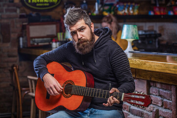 Guitars and strings. Bearded man playing guitar, holding an acoustic guitar in his hands. Music...