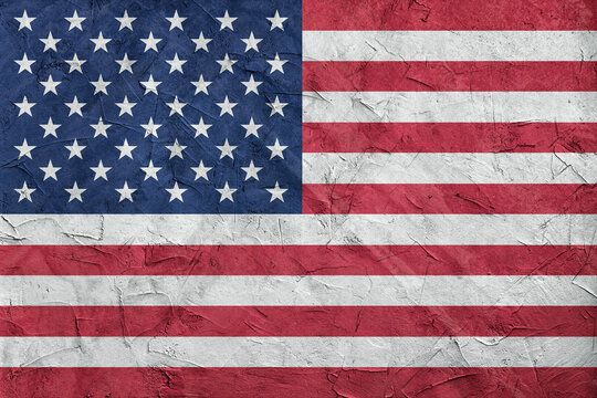 USA flag on stone wall, grunge background. USA flag depicted in bright paint colors on old relief plastering wall