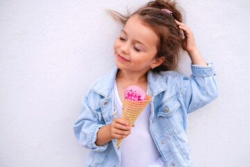 A girl in a denim blue jacket with a horn and a ball of pink ice cream straightens her hair flying...