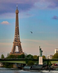 Eiffel Tower and the Liberty statue near the river Seine in Paris, during a sunset
