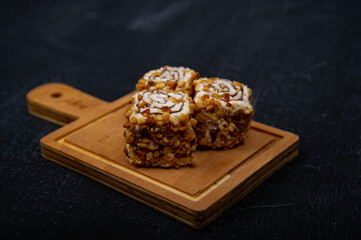 Turkish delight on wooden plate on black background