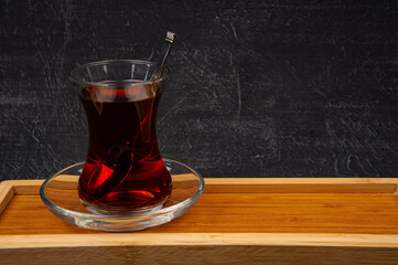 Turkish tea in wooden plate on black background