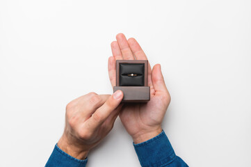 a man's hand holds a diamond engagement ring in a wooden elegant box, making a marriage proposal