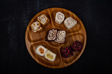 Turkish delight on wooden plate on black background