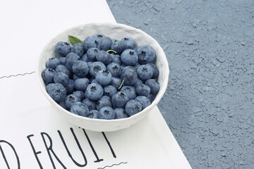 Blueberries in a handmade bowl. A white bowl with blueberries on a kitchen cloth.