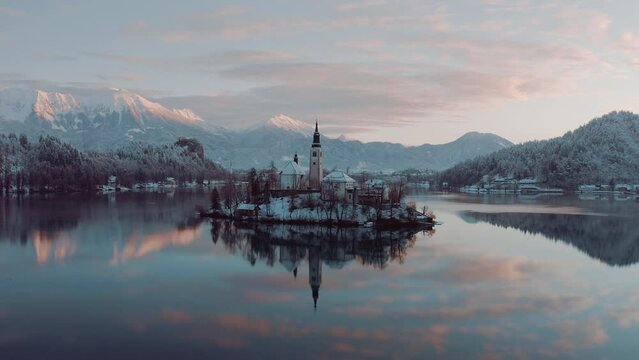 Close-up shot of Lake Bled, Slovenia, on a beautiful golden morning in winter time. Snowy mountains in the background. Peaceful nature, fresh air, clean blue water. Top travel destination. Green count