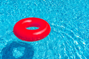 Red ring floating in blue swimming pool. Inflatable ring, rest concept