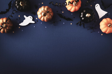 Halloween holiday background with party decorations of pumpkins, bats, ghosts on dark blue table...