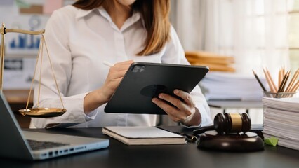 Justice and law concept.Male judge in a courtroom  with the gavel, working with tablet with, computer and  docking keyboard, eyeglasses, on table