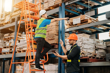 Fototapeta premium Warehouse manager wearing helmet pointing towards shelf using digital tablet and notepad in warehouse..
