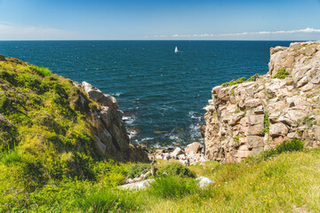 sailboat and steep cliffs of nothern Bornholm coastline at baltic sea, Denmark