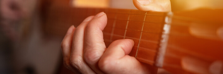 male hands elderly senior caucasian man holding and playing classical guitar close up at home. unprofessional faceless guitarist people play amateur music. domestic hobbies and leisure. banner. flare