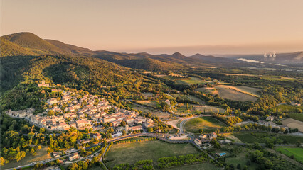 Panoramic drone view of one of the most beautiful French towns in southern France - Mirmande. Old historic town. Sunset over the surrounding mountains. Chimneys from the power plant in the distance