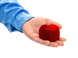 A man's hand holds a red velvet box like a heart. The concept of marriage proposal, engagement. Isolated on white background.