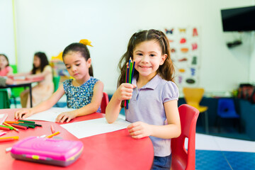 Preschooler girl feeling happy whole coloring in kindergarten
