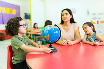 Student with glasses at a geography class using a globe
