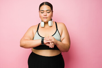 Beautiful obese woman in wearing sportswear looking at her watch