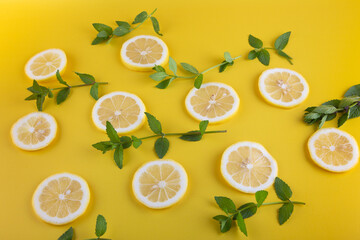 Lemon slices and green mint leaves pattern on grained yellow background.