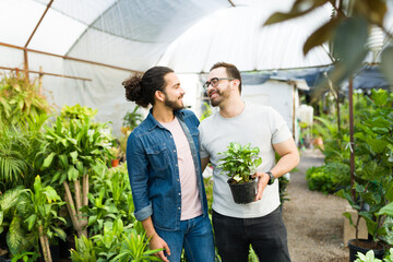 Gay couple hugging while choosing new green plants at the nursery garden - Powered by Adobe