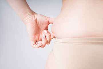 Overweight female body on gray background closeup, skin folds on an obese body