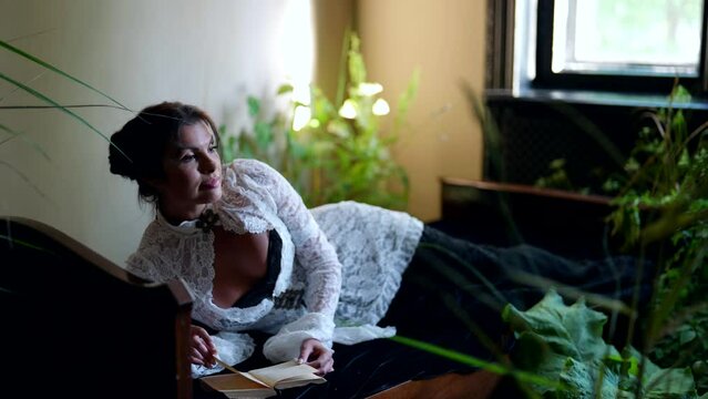 romantic busty woman in vintage dress is lying and reading book, sexy woman in historical interior